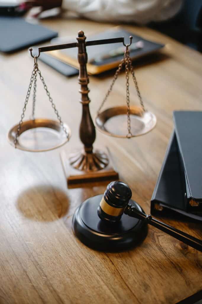 scales of justice and gavel on an office desk next to books