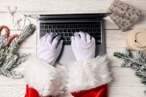 Person dressed in santa costume at laptop demonstrates holiday hackers